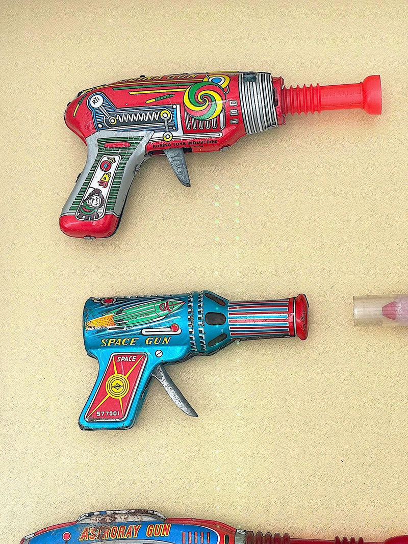 Mid century tinplate and plastic ray guns mounted in a white box frame