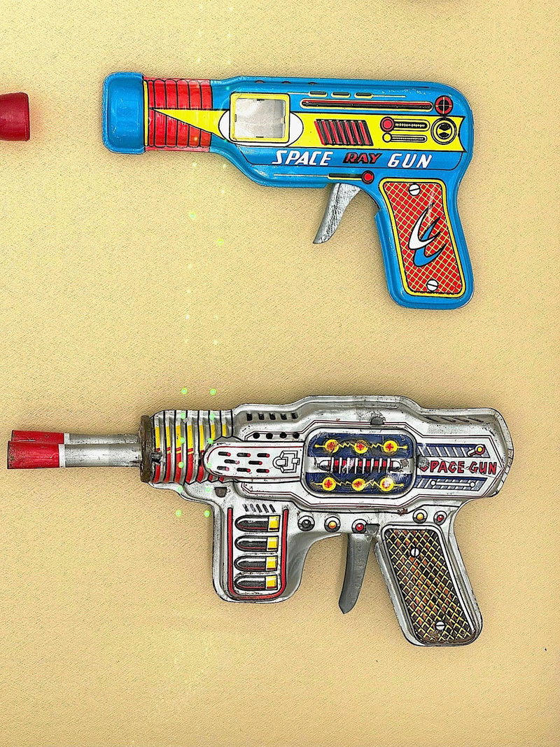 Mid century tinplate and plastic ray guns mounted in a white box frame