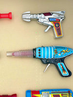 Mid century tinplate and plastic ray guns mounted in a white box frame
