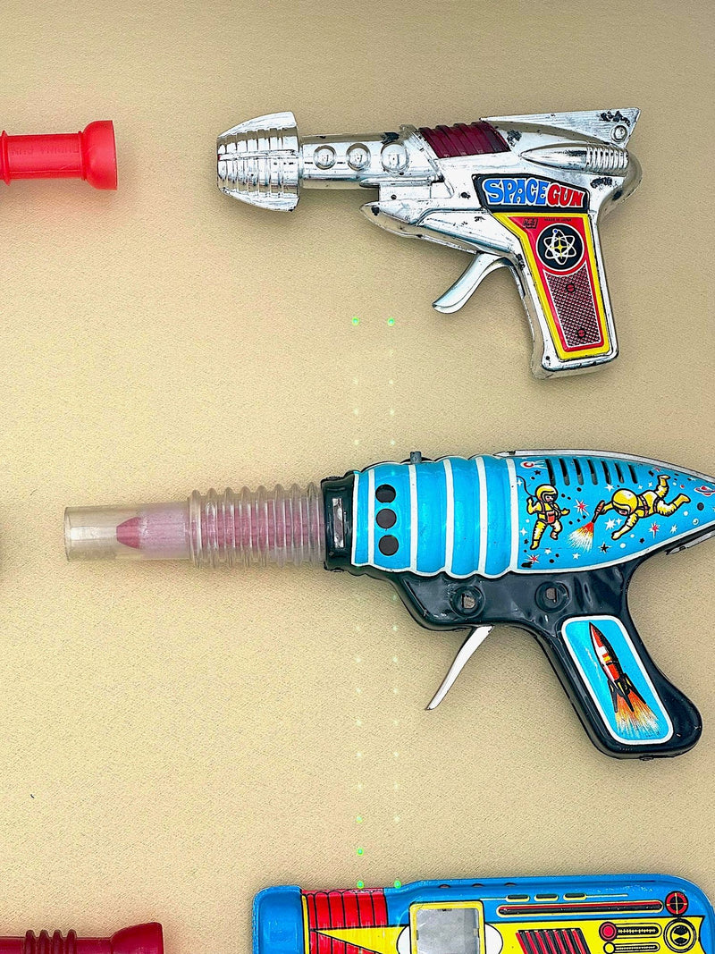 Mid century tinplate and plastic ray guns mounted in a white box frame