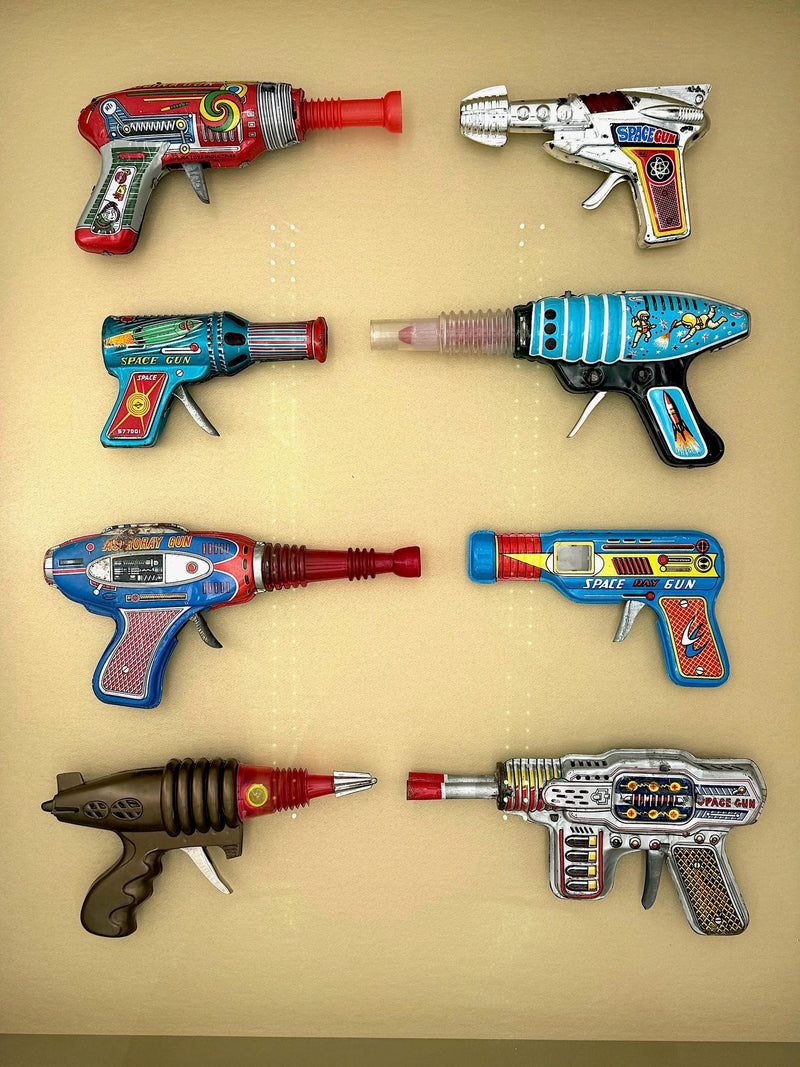 Mid century tinplate and plastic ray guns mounted in a white box frame