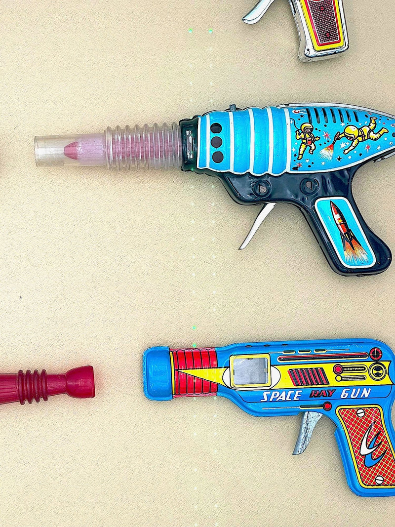 Mid century tinplate and plastic ray guns mounted in a white box frame