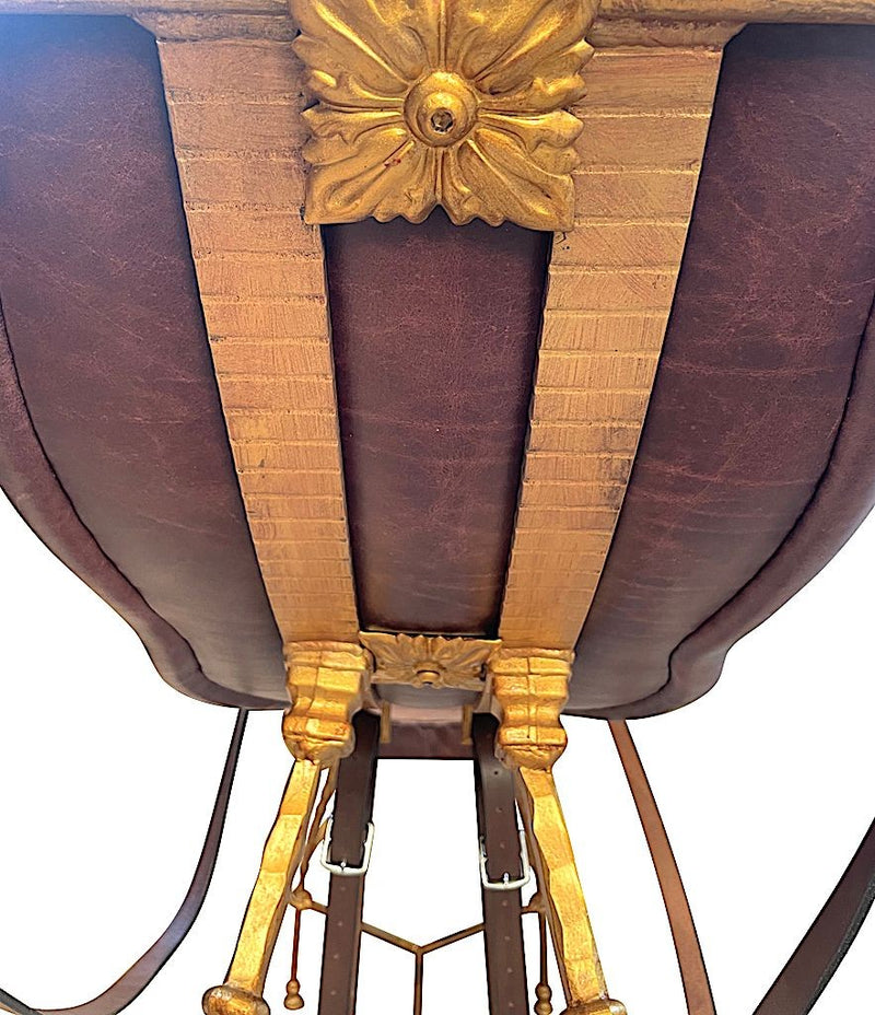 A Mark Brazier Jones "Tally Ho" chair a sculptural chair upholstered in a tan leather, with leather reigns, straps and steel stirrups on a stylised gilt wrought iron frame