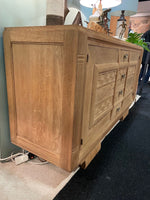 A French 1940s bleached oak sideboard in the style of Charles Dudouyt with two doors and four central drawers and relief front design