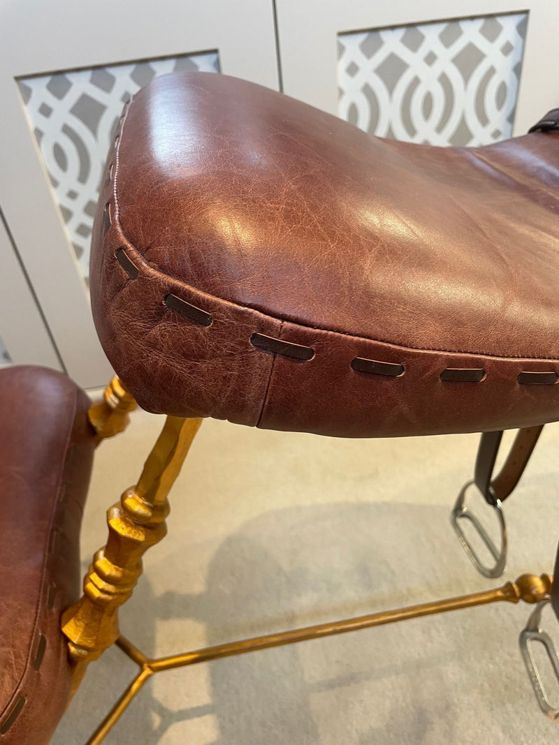 A Mark Brazier Jones "Tally Ho" chair a sculptural chair upholstered in a tan leather, with leather reigns, straps and steel stirrups on a stylised gilt wrought iron frame